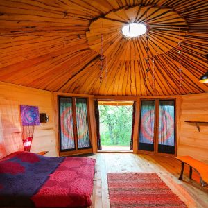 Hébergement insolite : yourte en bois avec un intérieur chaleureux et lumineux.