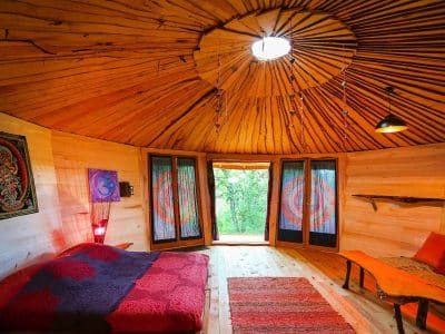 Hébergement insolite : yourte en bois avec un intérieur chaleureux et lumineux.