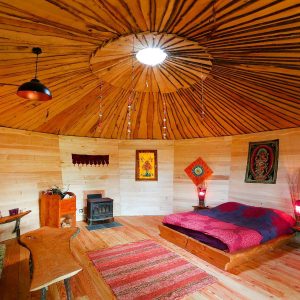 Hébergement insolite en yourte, intérieur chaleureux avec lit douillet et décor coloré.
