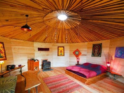 Hébergement insolite en yourte, intérieur chaleureux avec lit douillet et décor coloré.