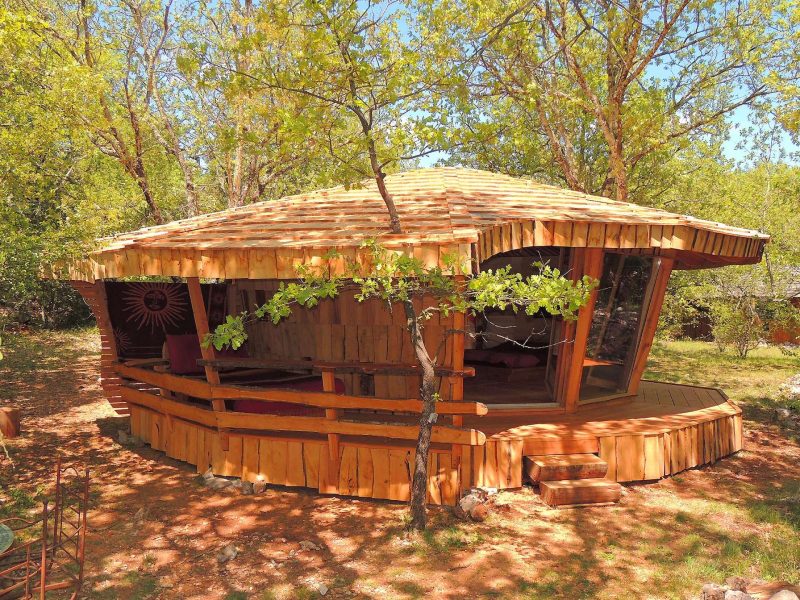 Cabane en bois originale, entourée darbres, offrant un cadre naturel apaisant.