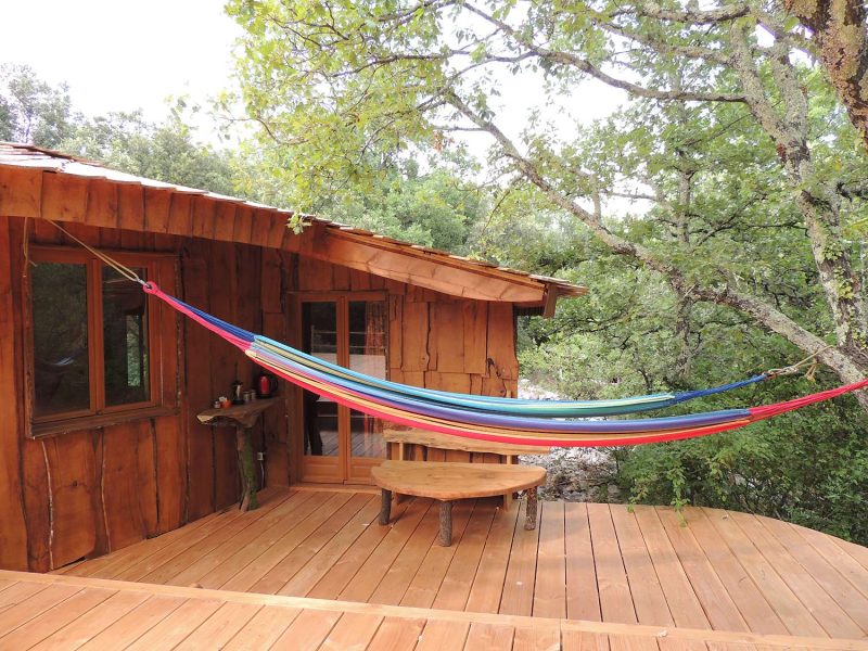 Cabane en bois dans le Languedoc-Roussillon, avec un hamac coloré suspendu.