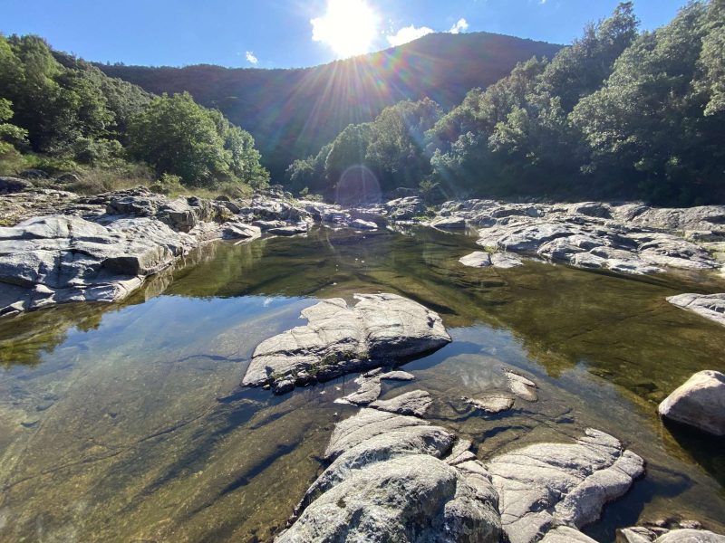 Hébergement en pleine nature, avec un ruisseau et des rochers baignés de lumière.