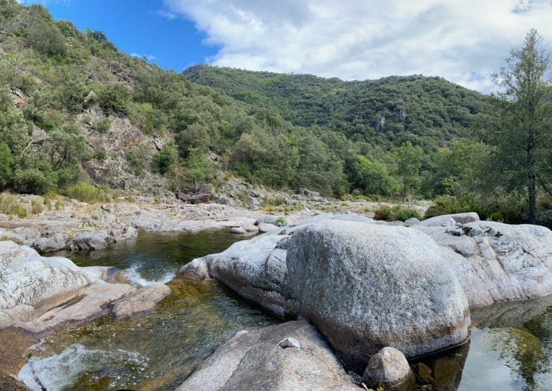Hébergement en pleine nature, avec des rochers et une rivière entourée de verdure.