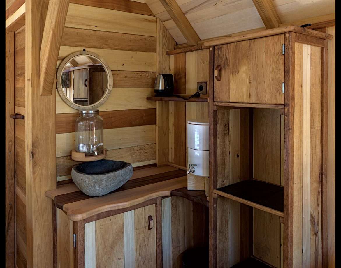 Hébergement insolite en Aquitaine : intérieur en bois chaleureux avec lavabo en pierre.