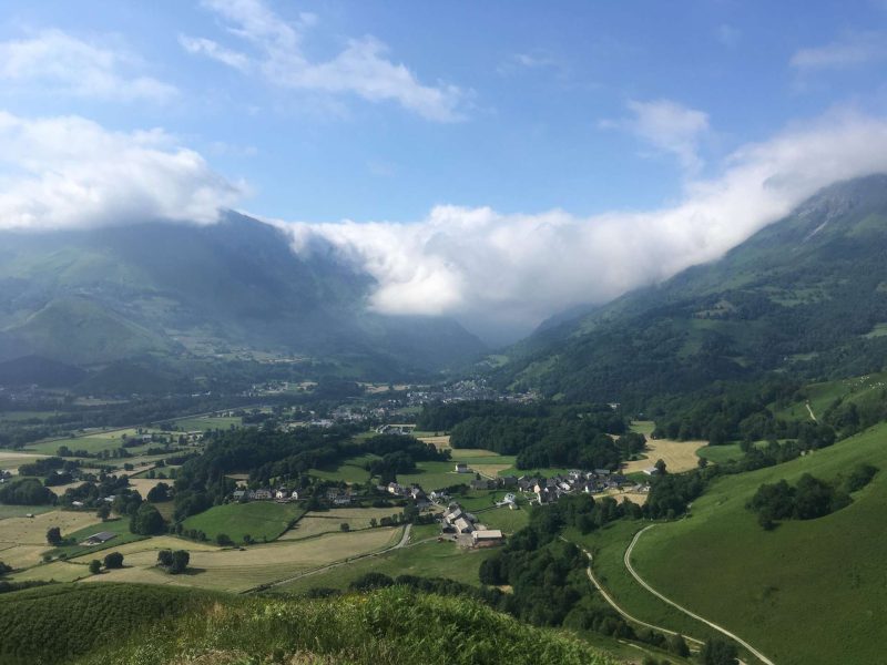 Chalet en montagne avec vue panoramique sur les vallées verdoyantes et les nuages.