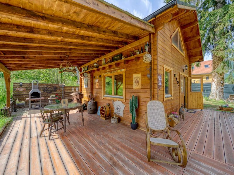 Chalet en bois avec terrasse ensoleillée et coin barbecue accueillant.