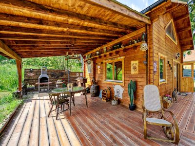 Cabane en bois avec terrasse ensoleillée et coin barbecue, idéale pour se détendre.