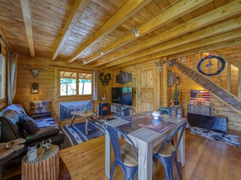 Chalet en bois chaleureux avec un intérieur rustique et des fenêtres lumineuses.