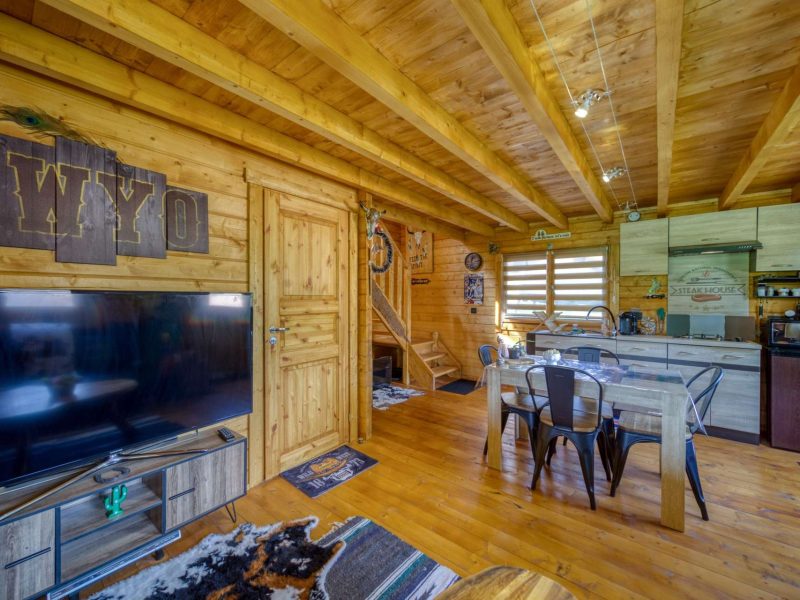 Chalet en bois chaleureux avec cuisine ouverte et décoration rustique.