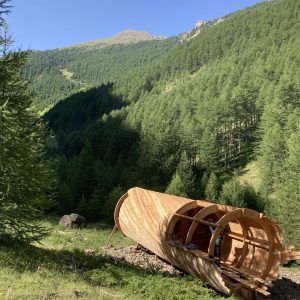 Hébergement insolite en bois, type cabane, entouré de forêts verdoyantes en montagne.