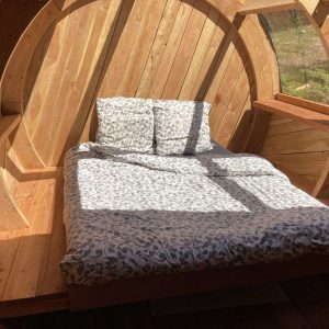 Hébergement insolite en forme de tonneau, lit douillet baigné de lumière naturelle.