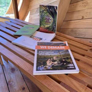 Hébergement insolite en bois, avec des livres sur une table en terrasse ensoleillée.