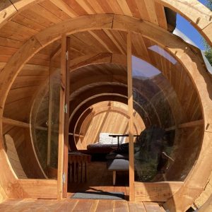 Hébergement insolite en forme de tonneau en bois, offrant une vue panoramique.