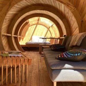 Hébergement insolite en forme de tonneau, intérieur en bois chaleureux et confortable.