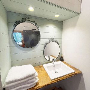 Espace de salle de bain dans un hébergement insolite en Pays de la Loire, avec miroirs élégants.