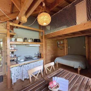 Cabane en bois avec cuisine équipée et lit douillet, ambiance chaleureuse.