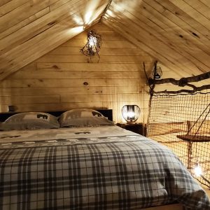 Chalet en bois cosy avec lit double et éclairage chaleureux dans les Vosges.