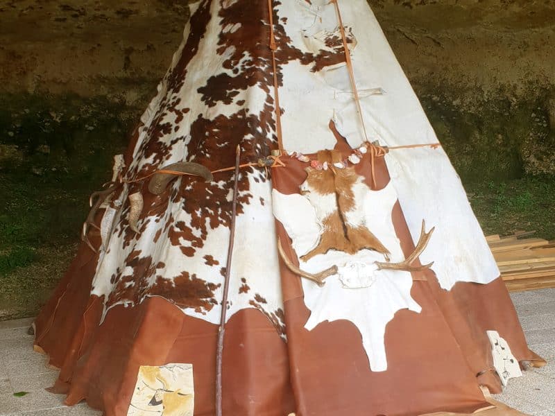 Tipi traditionnel en Aquitaine, décoré de motifs naturels et installé sous une roche.