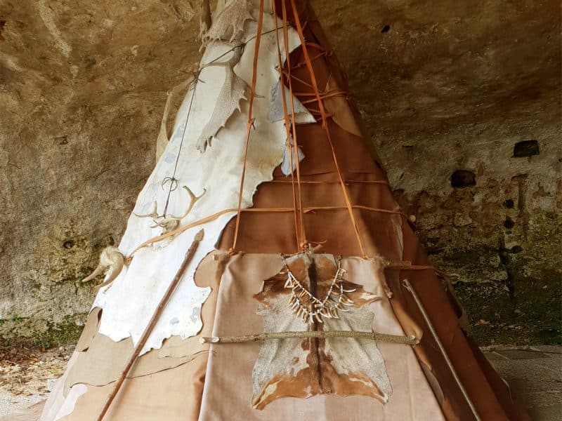 Tipi en Aquitaine, décoré de peaux et installé sous une roche naturelle.