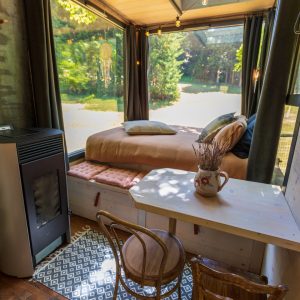 Cabane en verre dans les arbres, avec lit douillet et vue sur la nature.