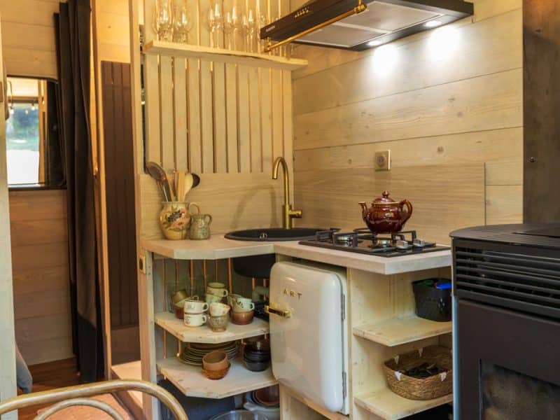 Cuisine moderne dun chalet en bois, avec un évier doré et des étagères en bois.