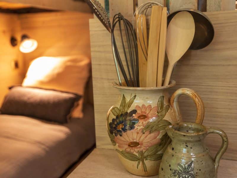 Hébergement en cabane avec cuisine rustique et ustensiles en pot décoratif.