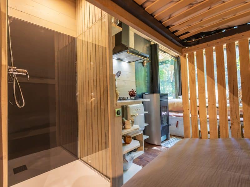 Cabane moderne avec salle de bain, cuisine équipée et ambiance boisée.