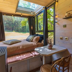 Chalet en bois avec vue sur la nature, lit confortable et décor chaleureux.