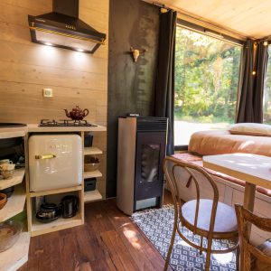 Hébergement insolite en Auvergne-Rhône-Alpes, intérieur cosy avec kitchenette et vue sur la nature.