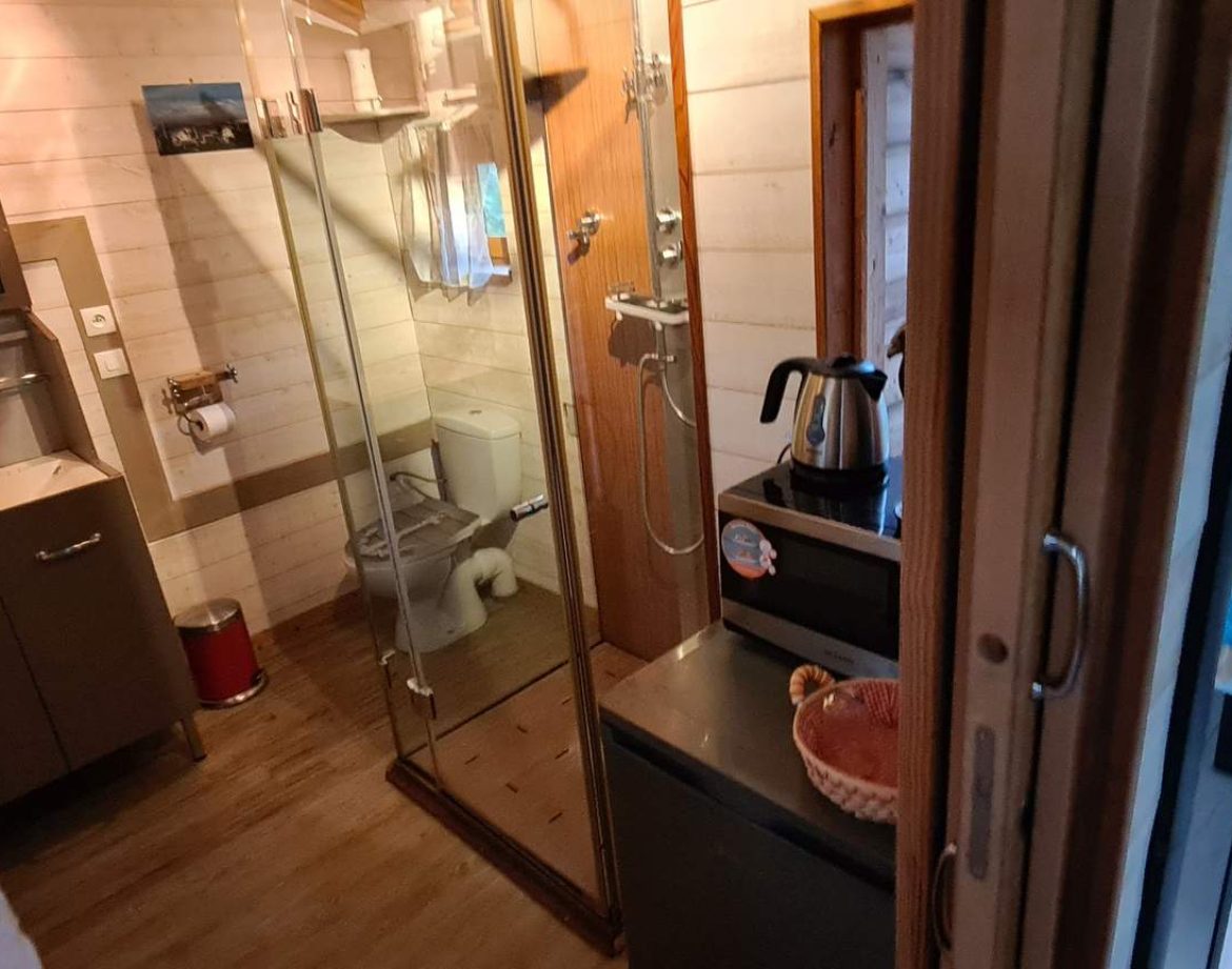 Hébergement insolite en Corse : intérieur moderne avec douche vitrée et lit coloré.