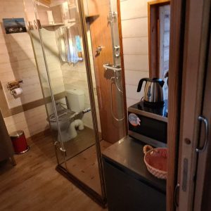 Hébergement insolite en Corse : intérieur moderne avec douche vitrée et lit coloré.