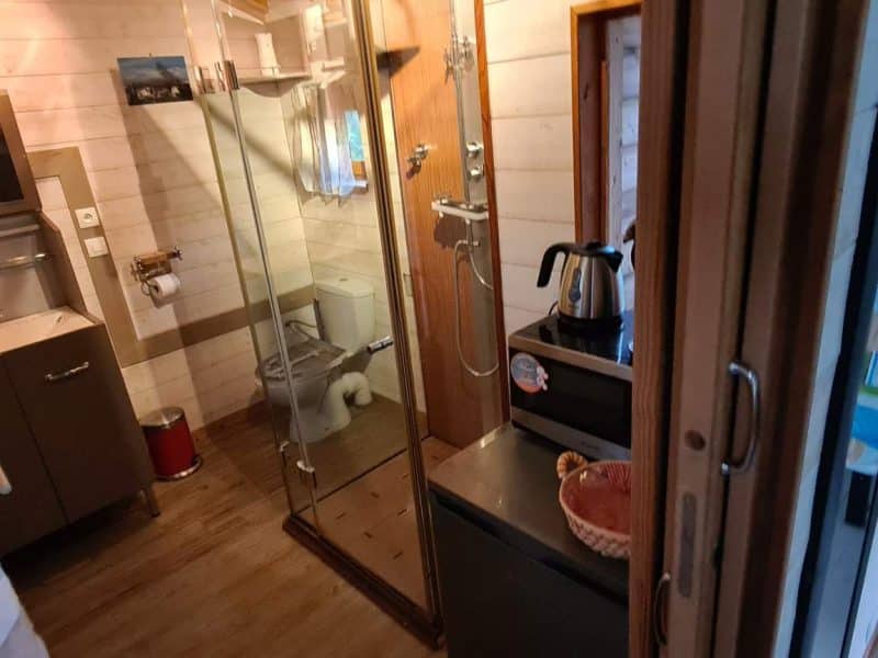 Hébergement insolite en Corse : intérieur moderne avec douche vitrée et lit coloré.