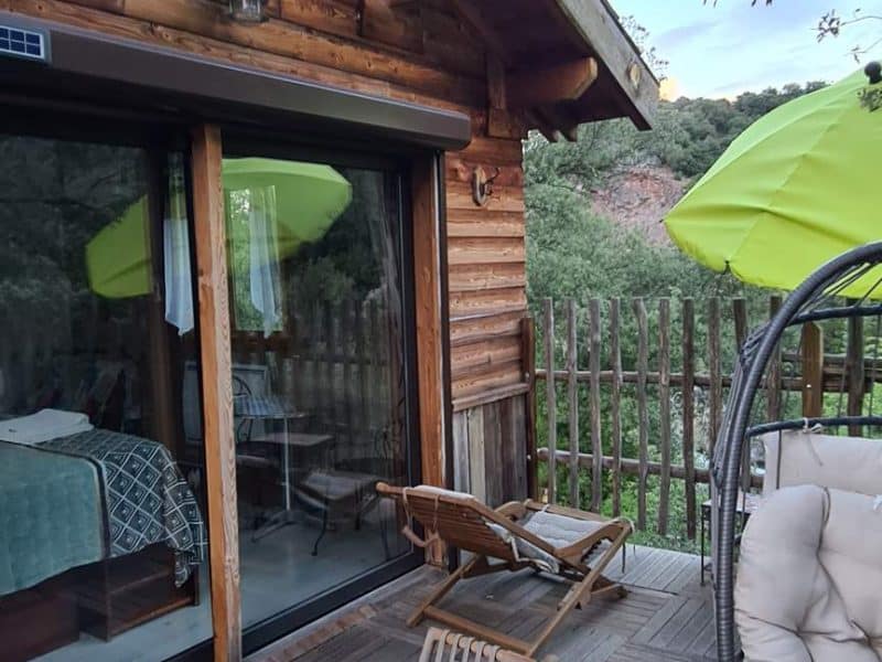 Cabane en bois en Corse avec terrasse ensoleillée et vue sur la nature.