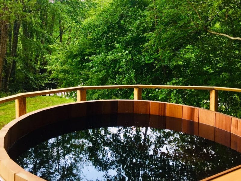 Bain nordique en bois entouré dune verdure luxuriante, idéal pour se détendre.