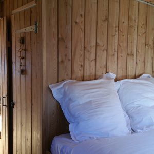 Chalet en bois chaleureux avec lit douillet et vue sur la terrasse ensoleillée.