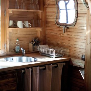 Hébergement insolite en bois avec une cuisine cosy et un petit miroir vintage.