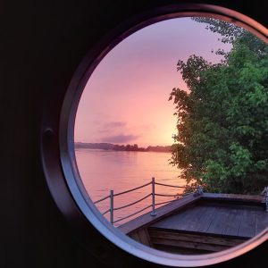 Cabane flottante avec vue circulaire sur un coucher de soleil au bord de leau.