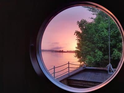 Cabane flottante avec vue circulaire sur un coucher de soleil au bord de leau.