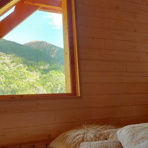 Chalet en bois avec vue panoramique sur les montagnes, intérieur chaleureux et confortable.