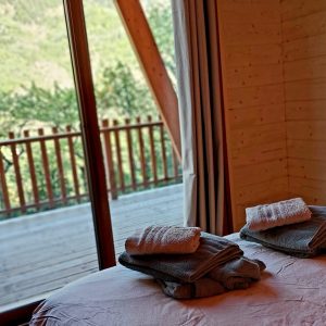 Chalet en bois avec vue sur la nature, linge de lit soigneusement plié.