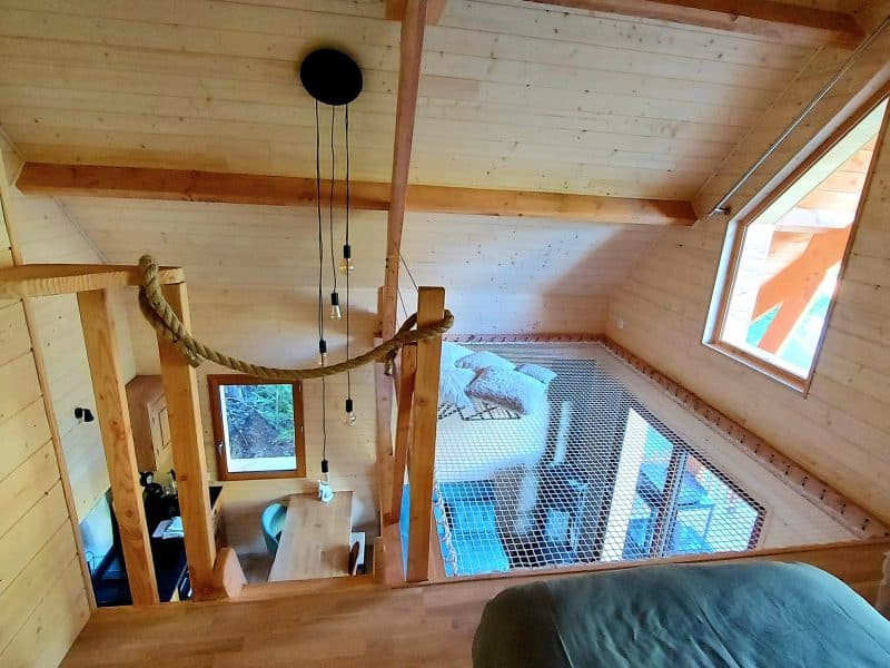 Chalet en bois avec mezzanine, baigné de lumière naturelle et décor chaleureux.