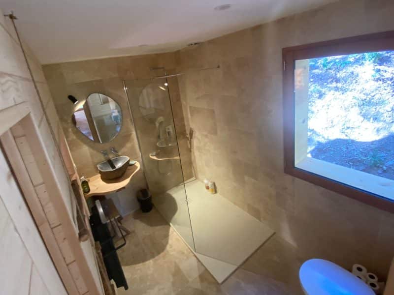 Salle de bain moderne dun chalet, avec douche en verre et fenêtre lumineuse.