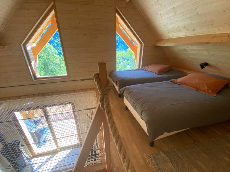 Chalet en bois avec deux lits et grandes fenêtres offrant une vue panoramique.