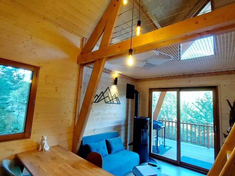 Cabane en bois moderne avec grandes fenêtres et décoration chaleureuse.