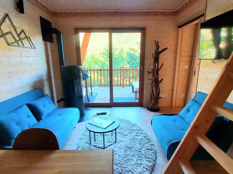 Chalet en bois avec un salon lumineux et des canapés bleus confortables.