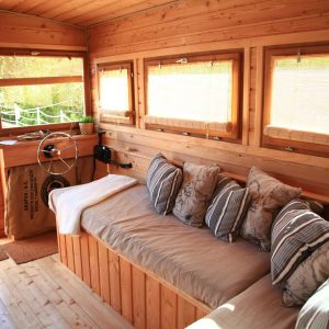 Hébergement insolite en bois avec un salon lumineux et confortable, idéal pour se détendre.