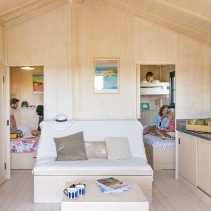 Cabane en bois en Bretagne, intérieur lumineux avec canapés et décor coloré.