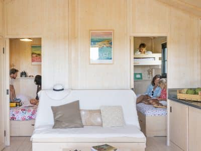 Cabane en bois en Bretagne, intérieur lumineux avec canapés et décor coloré.