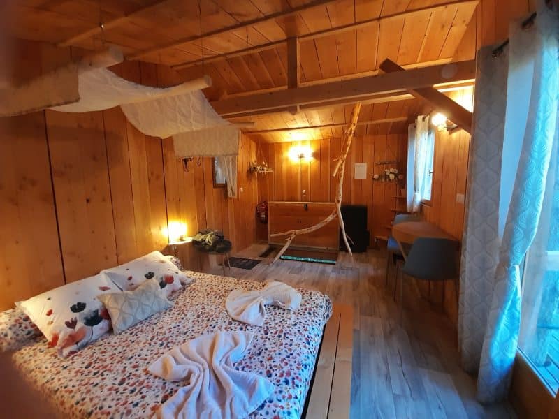 Chalet en bois chaleureux avec lit douillet et décoration naturelle à Auvergne-Rhône-Alpes.